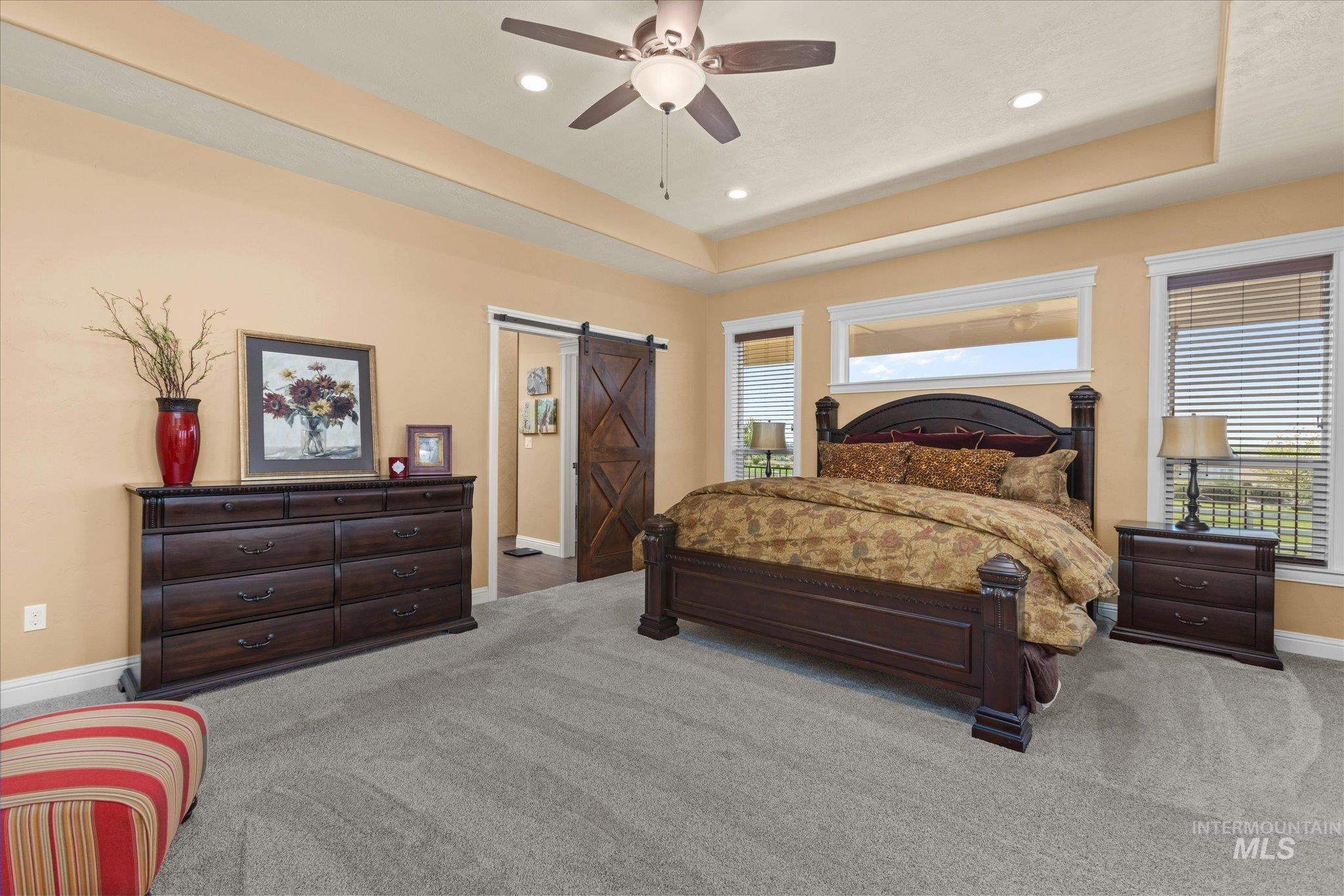 13683 Hockberger Ranch Road Caldwell, ID 83607 - Photo 20 of 50 Tray ceiling with recessed lighting, ceiling fan, grey carpet flooring, multiple windows, and a wood-finish barn door