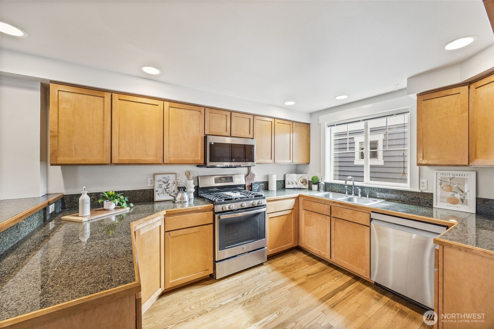 910 Northwest 85th Street, Unit B Seattle, WA 98117 - Photo 12 of 21 a kitchen with stainless steel appliances granite countertop a stove top oven a sink dishwasher a refrigerator and cabinets with wooden floor