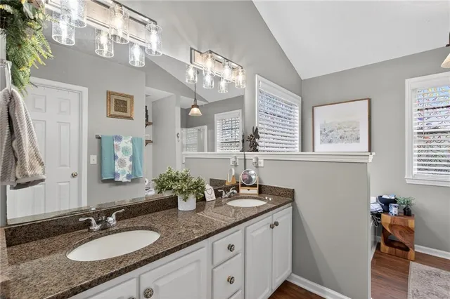 a bathroom with a granite countertop double vanity sink and a mirror