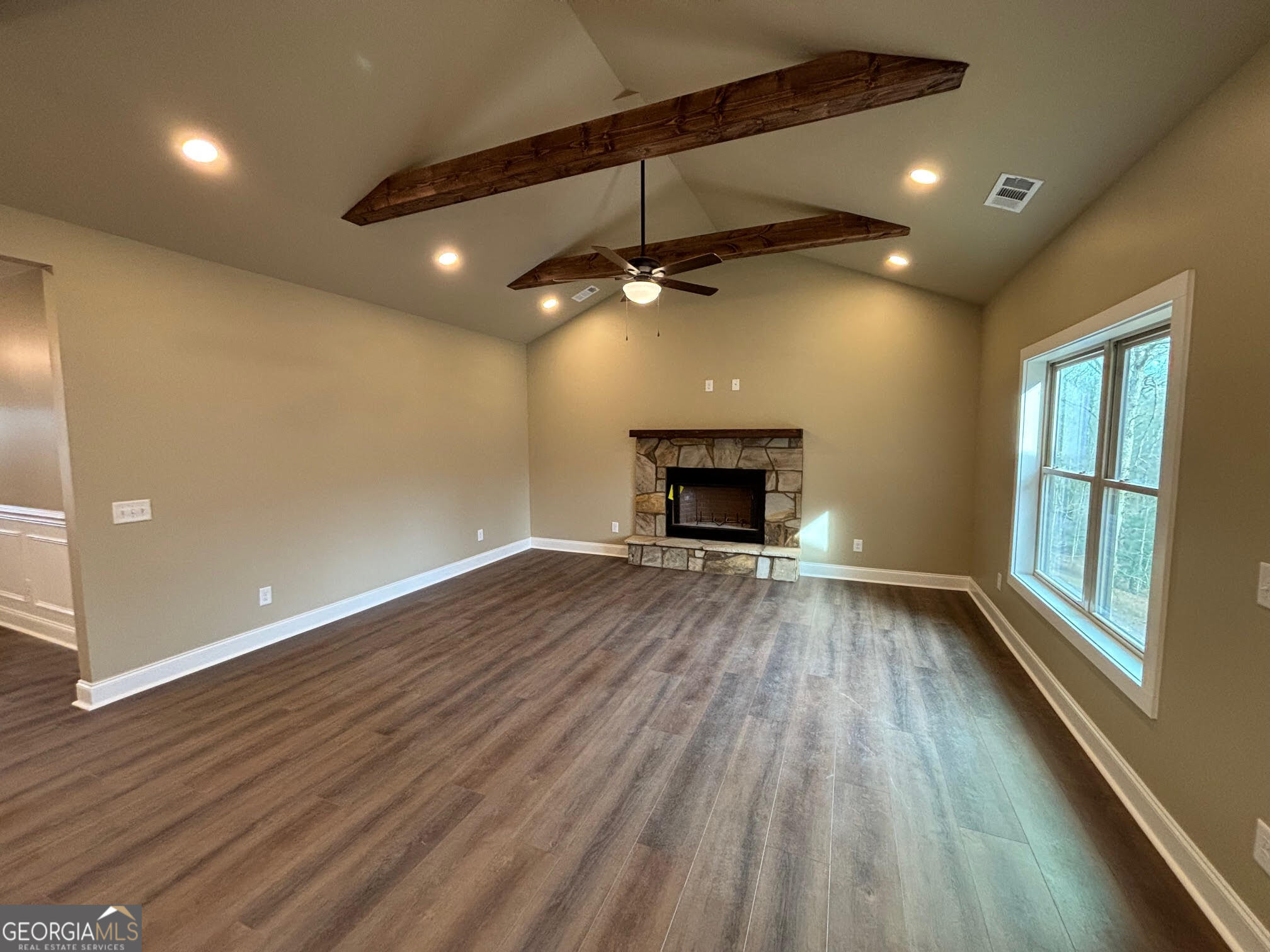 178 Samson Way Cleveland, GA 30528 - Photo 7 of 32 an empty room with wooden floor a ceiling fan a fireplace and windows