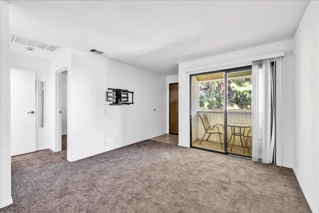 a view of kitchen and empty room with cabinet