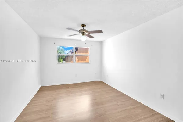 an empty room with a window and a ceiling fan
