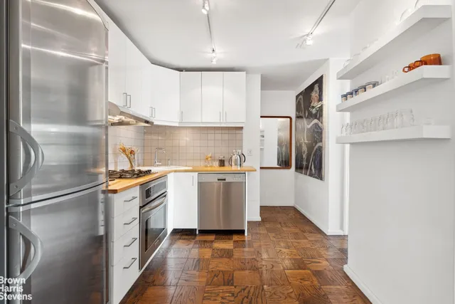 a kitchen with stainless steel appliances granite countertop a refrigerator a stove and a sink with wooden floor