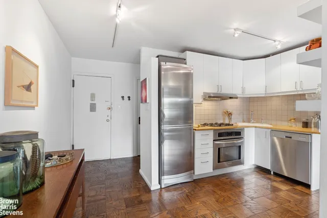 a kitchen with granite countertop a refrigerator oven a sink dishwasher and white cabinets next to a window