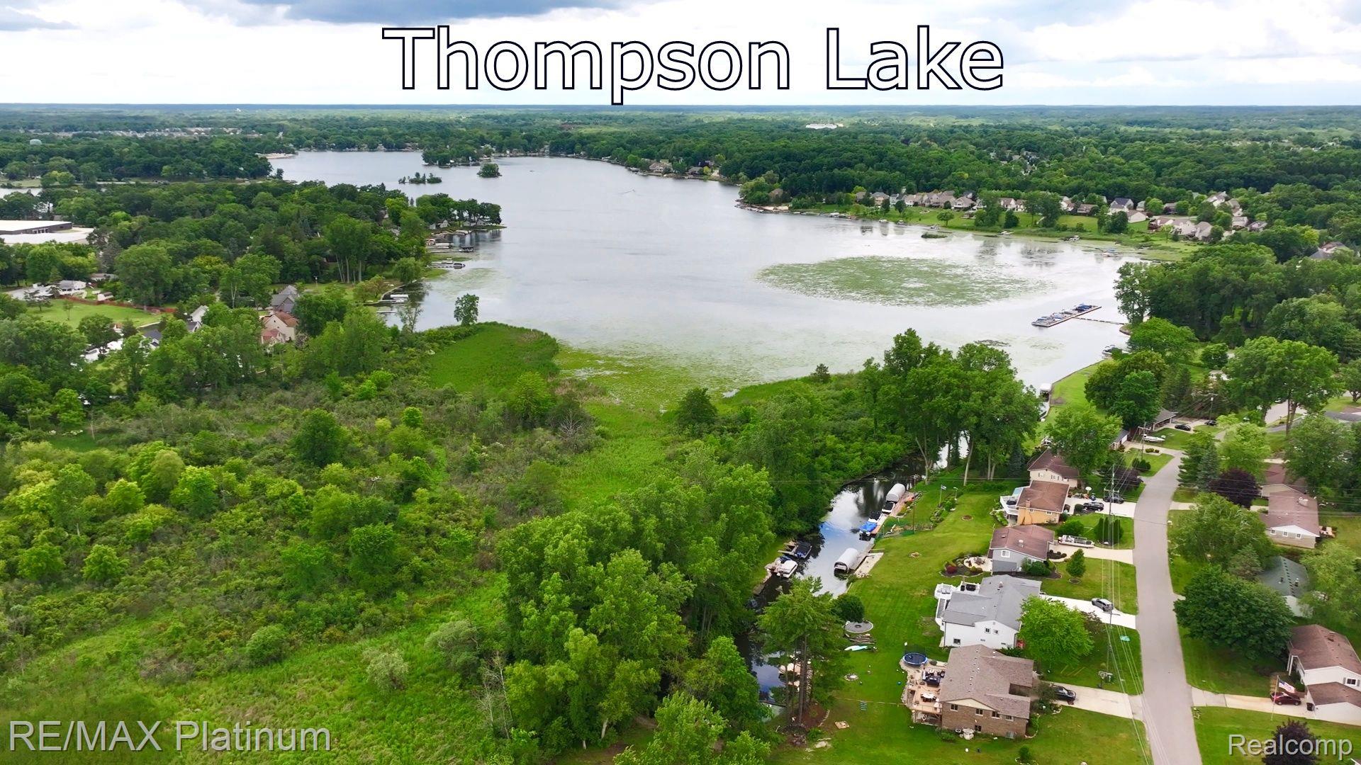 2401 Golf Club Road Howell, MI 48843 - Photo 7 of 8 Thompson Lake with surrounding residential properties, dense tree lines, and a dedicated waterway with boat access