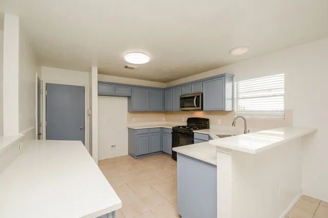 a large white kitchen with a window and refrigerator