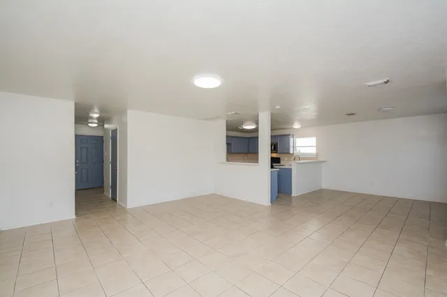 an empty room with kitchen and windows