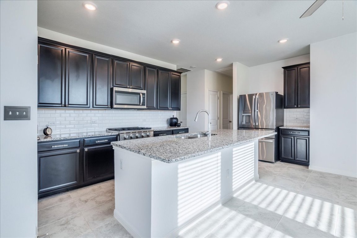 101 Otella Street Georgetown, TX 78628 - Photo 5 of 33 a kitchen with stainless steel appliances granite countertop a sink stove and refrigerator