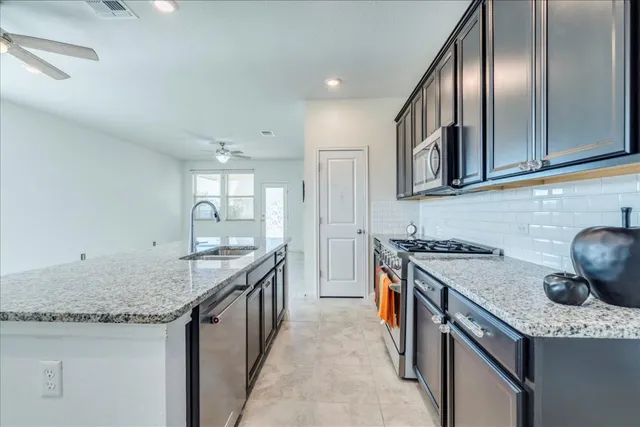 a kitchen with granite countertop stainless steel appliances a sink stove and cabinets