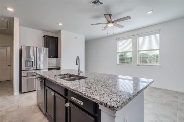 a kitchen with stainless steel appliances granite countertop a sink refrigerator and cabinets