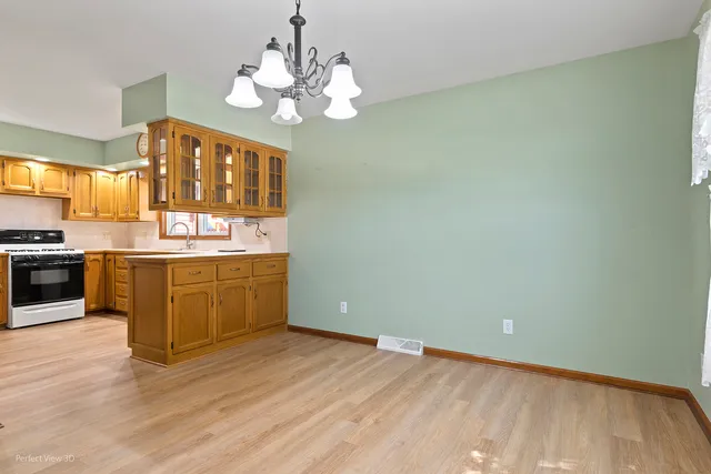 a kitchen with stainless steel appliances granite countertop a stove a sink dishwasher and wooden cabinets with wooden floor