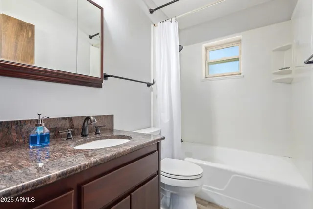 a bathroom with a granite countertop sink a toilet a mirror and shower