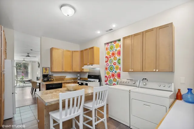 a white kitchen with stainless steel appliances granite countertop a stove a sink and a refrigerator
