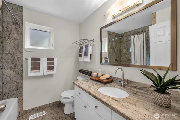 a bathroom with a granite countertop sink a toilet and a mirror