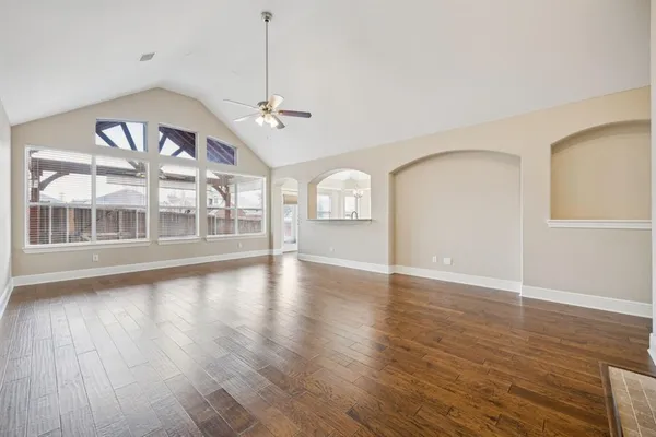a view of an empty room with wooden floor and a window