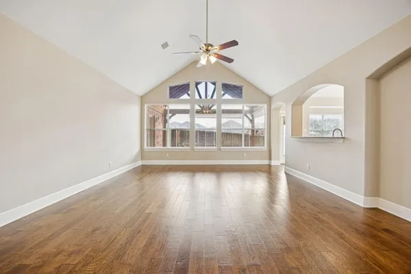 an empty room with wooden floor fan and windows