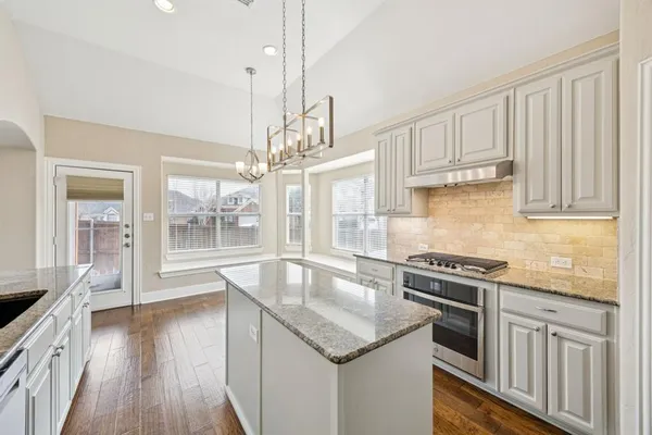 a kitchen with stainless steel appliances granite countertop a sink a stove and a wooden floors