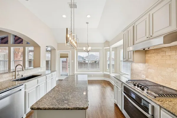 a open kitchen with granite countertop a stove a sink dishwasher and cabinets with wooden floor