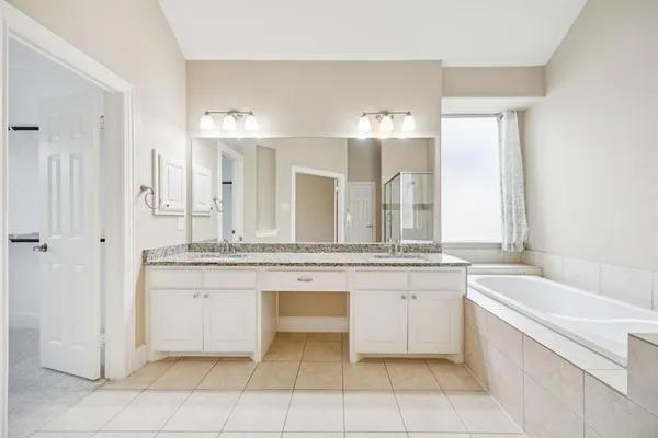 a bathroom with a granite countertop bathtub a sink and a mirror