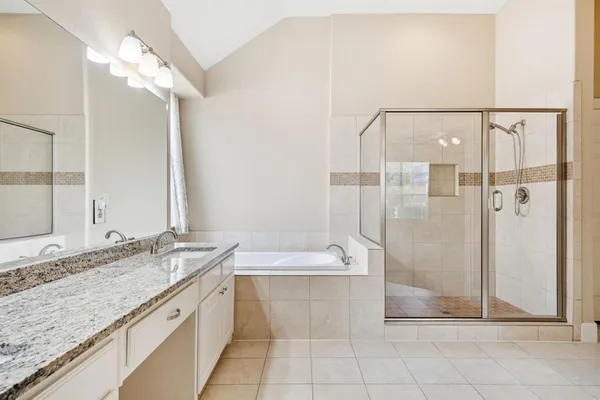 a bathroom with a granite countertop sink a mirror and a bathtub