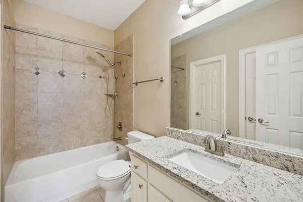 a bathroom with a granite countertop toilet a sink and a bathtub