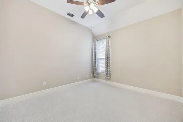 an empty room with a chandelier fan and windows