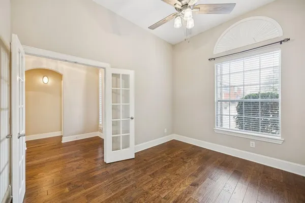 an empty room with wooden floor cabinet and windows
