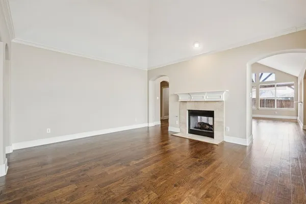 a view of an empty room with wooden floor fireplace and a window