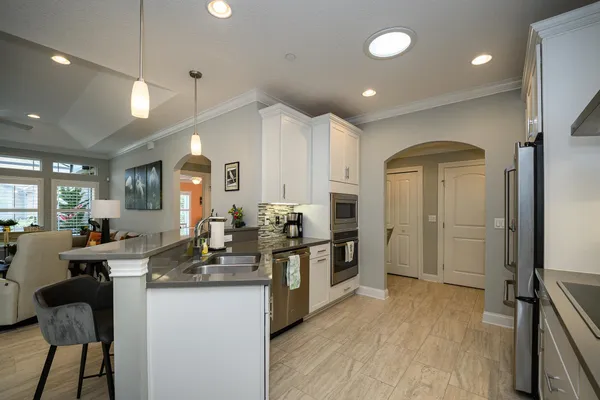 a kitchen with stainless steel appliances granite countertop a stove a sink and white cabinets with wooden floor