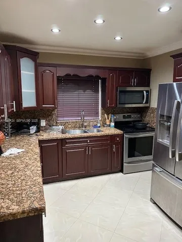 a kitchen with stainless steel appliances kitchen island granite countertop a stove sink and cabinets