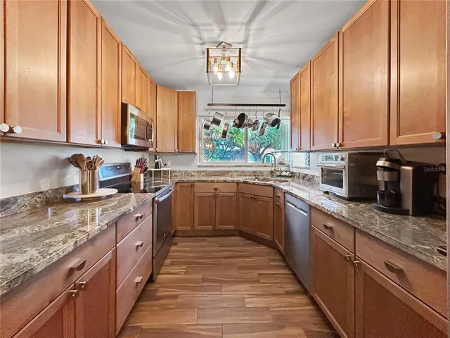 a kitchen with stainless steel appliances granite countertop a sink a stove and cabinets