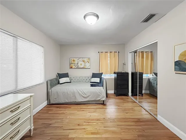 a spacious bedroom with a bed and wooden floor