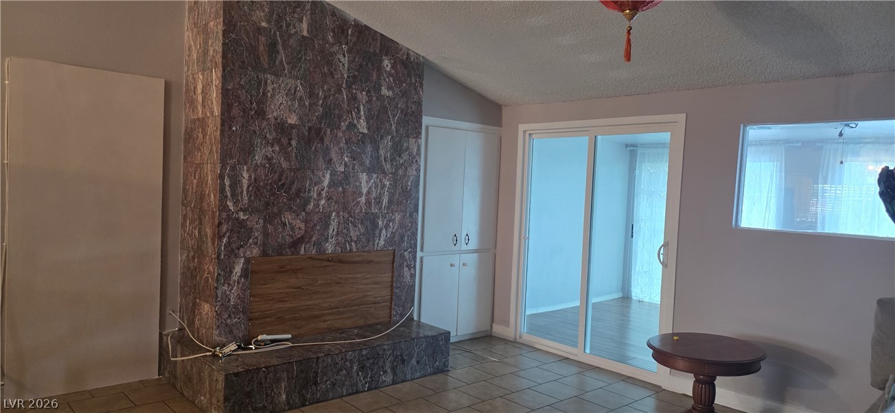 A floor-to-ceiling tiled fireplace stands out against the vaulted ceiling and sliding glass doors.