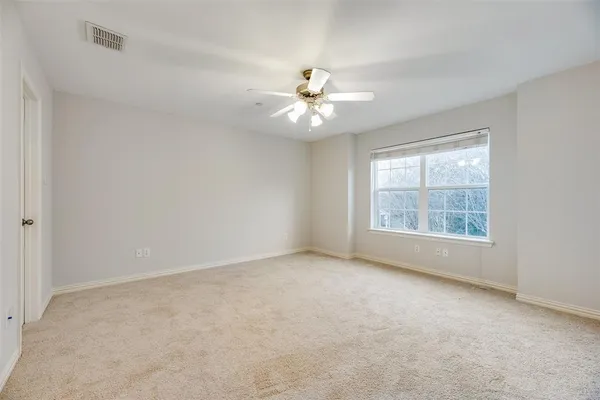 an empty room with a window and a ceiling fan