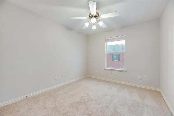 an empty room with a chandelier fan and windows
