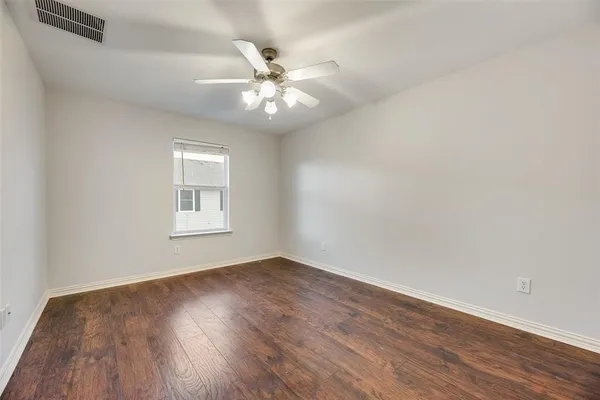 an empty room with wooden floor fan and windows