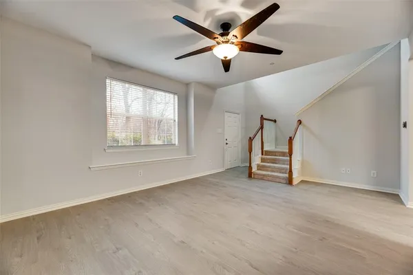 an empty room with windows and ceiling fan