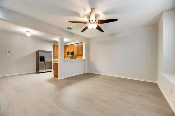 an empty room with ceiling fan and windows