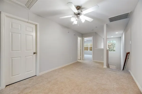 an empty room with fan and hallway view