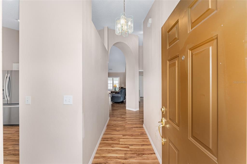 2121 Vindale Road Tavares, FL 32778 - Photo 5 of 37 a view of a hallway with wooden floor and a chandelier