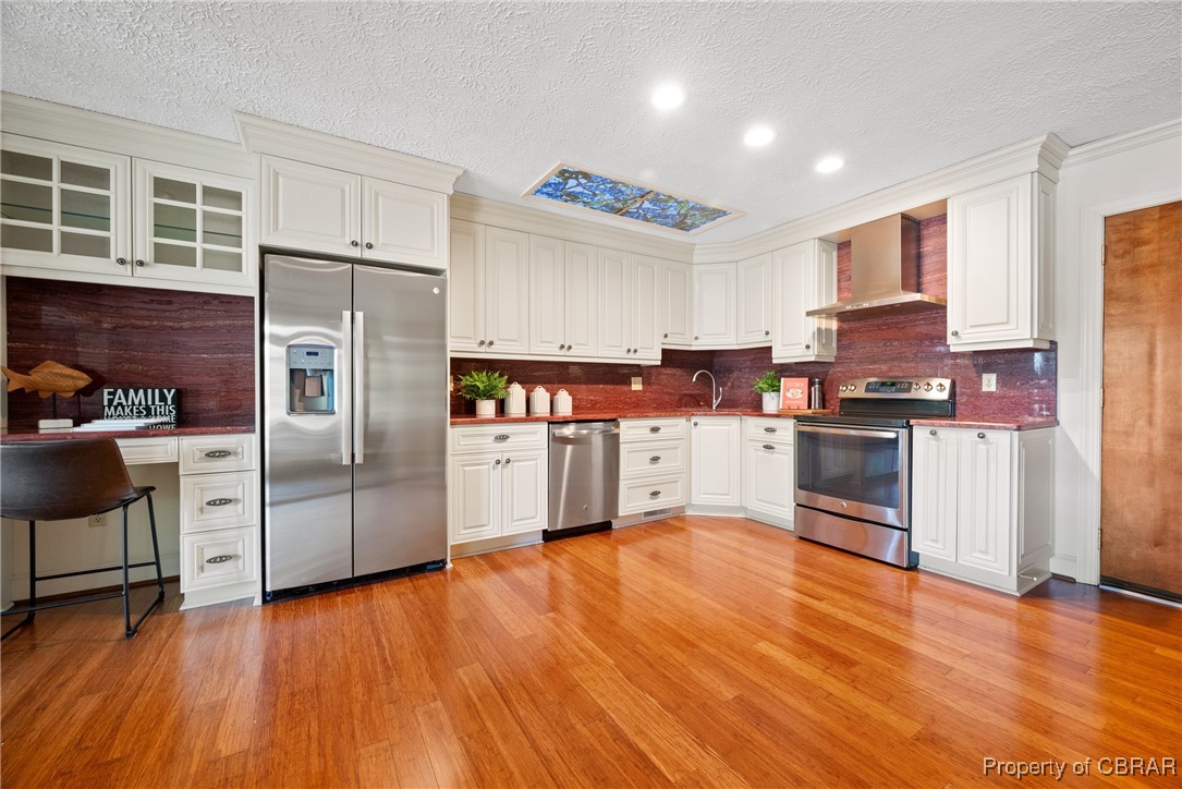 118 Paradise Point Road Yorktown, VA 23692 - Photo 14 of 50 Kitchen featuring light wood-type flooring, wall chimney exhaust hood, stainless steel appliances, sink, and white cabinetry
