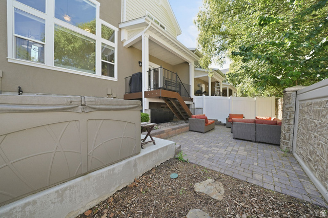 7872 Farm House Lane Midvale, UT 84047 - Photo 32 of 39 Paved patio area featuring a hot tub, privacy fencing, and a multi-level deck structure with stairs