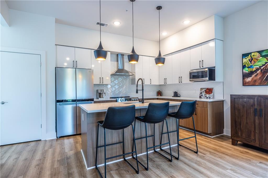 112 Rogers Street Southeast, Unit 208 Atlanta, GA 30307 - Photo 5 of 44 a kitchen with stainless steel appliances granite countertop a refrigerator a sink a stove a dining table and chairs with wooden floor