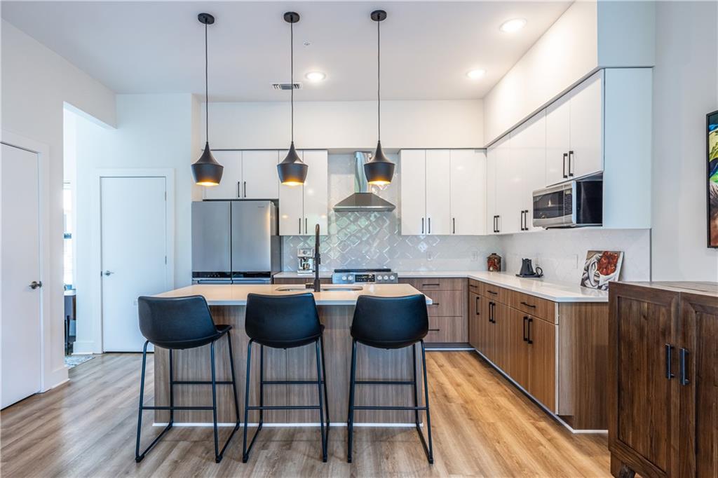 112 Rogers Street Southeast, Unit 208 Atlanta, GA 30307 - Photo 9 of 44 a kitchen with stainless steel appliances granite countertop a kitchen island a stove a sink a dining table and chairs with wooden floor