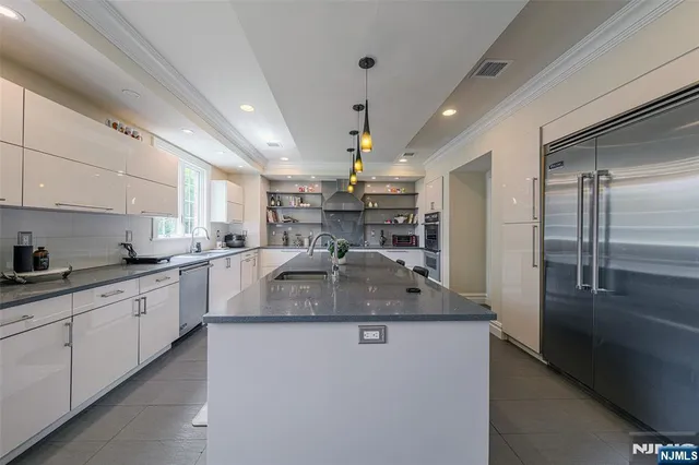a kitchen with stainless steel appliances granite countertop a sink refrigerator and cabinets