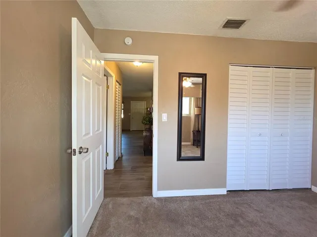 en view of a hallway with wooden floor and a bathroom