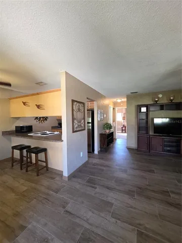 a view of a living room a kitchen island with furniture and wooden floor