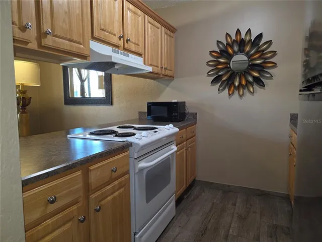 a kitchen with stainless steel appliances a stove a chimney and cabinets