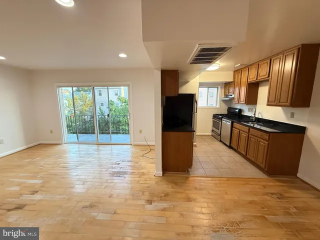a view of a kitchen with kitchen island a large counter top space a sink stainless steel appliances and cabinets