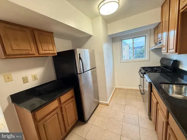 a kitchen with granite countertop a refrigerator stove and sink